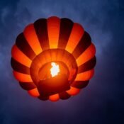 Hot air balloon floating over the Serengeti at sunrise with wildlife below